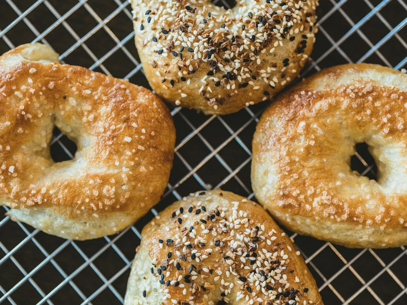 Golden everything and sesame bagels on a cooling rack