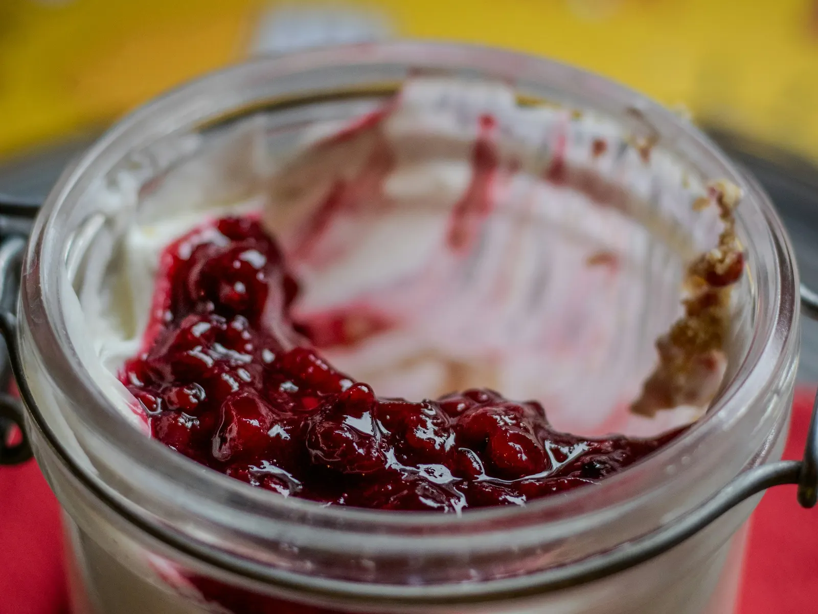 Creamy cheesecake dessert in a glass jar topped with berry compote