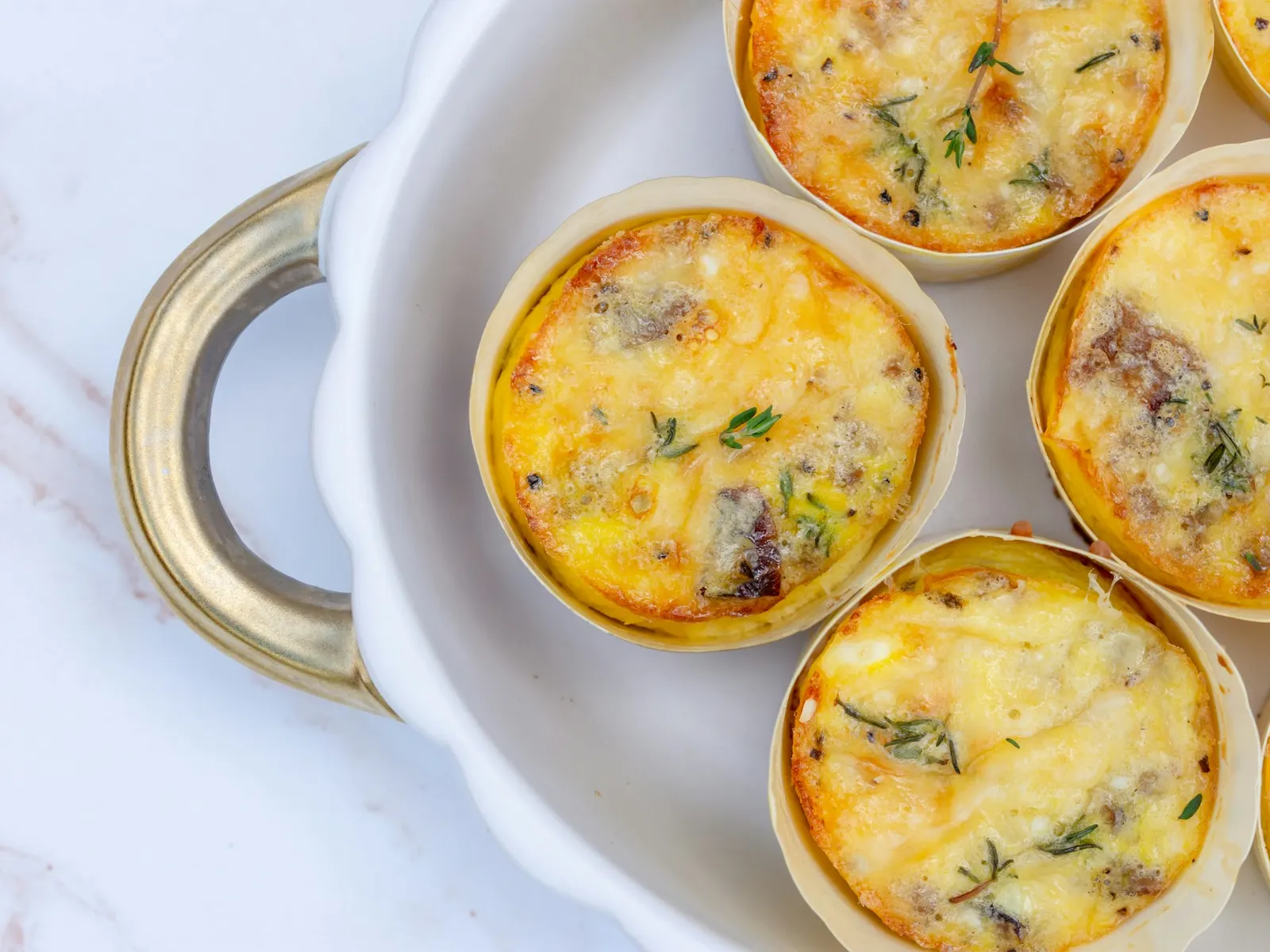 Egg bites topped with melted cheese on a white plate