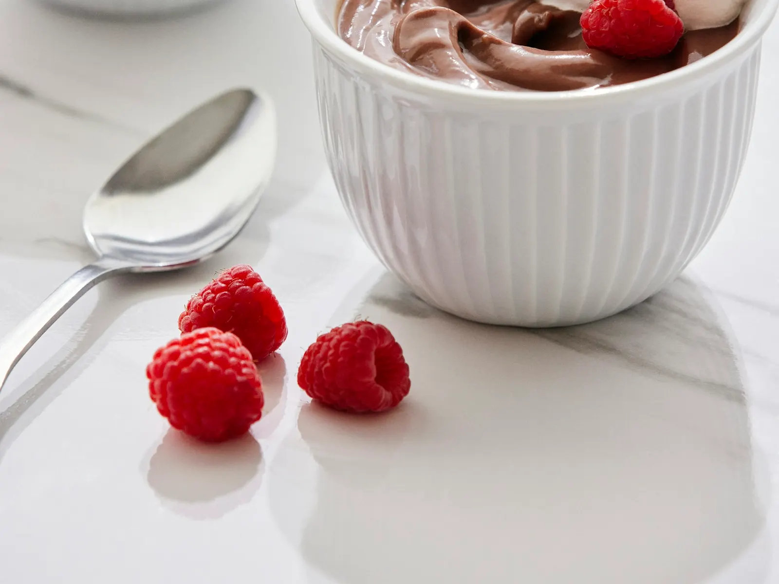 Two bowls of chocolate mousse with raspberries